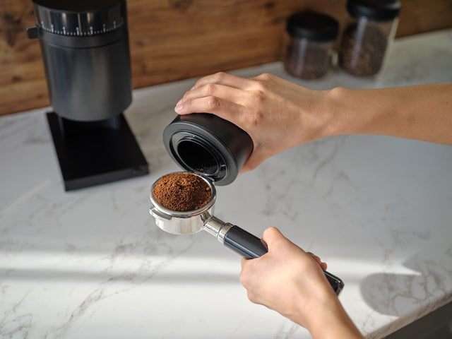 Fellow Opus Grinder, Matte Black, from Clive Coffee, person adding coffee to portafilter, lifestyle