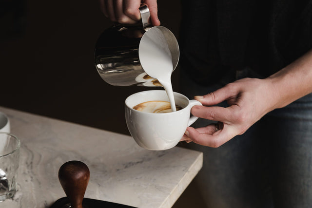 Cafelat Frothing Pitcher pouring a cappuccino, Clive Coffee - Lifestyle