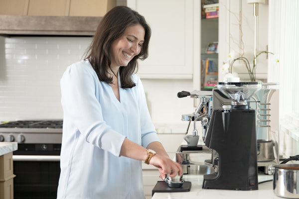 Woman making an espresso on the LUCCA Atom 75 espresso grinder with the LUCCA M58 espresso machine